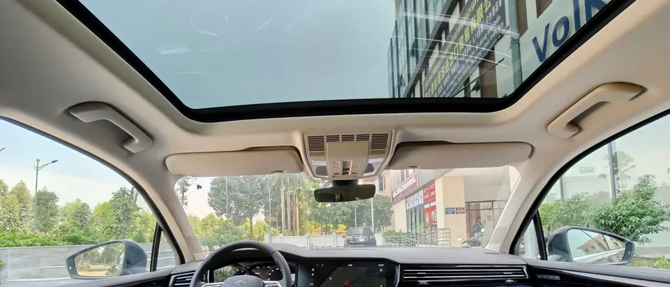 An SUV cabin seen from the back seat, a panoramic glass panel overhead and a clear windshield ahead